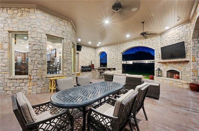 view of patio with an outdoor stone fireplace, ceiling fan, exterior kitchen, and a grill