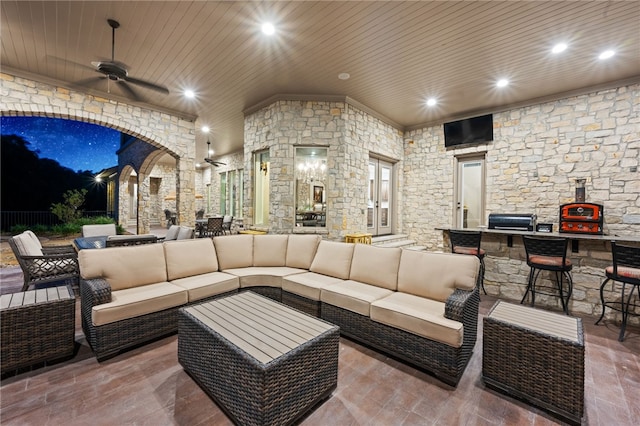 patio at twilight featuring a bar, an outdoor living space, and ceiling fan