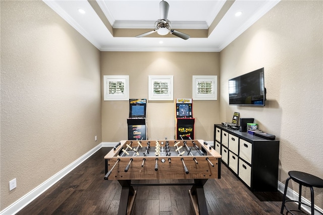 rec room featuring a raised ceiling, ceiling fan, dark wood-type flooring, and ornamental molding