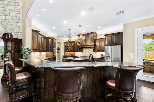 bar with hanging light fixtures, decorative backsplash, ornamental molding, dark hardwood / wood-style flooring, and stainless steel appliances