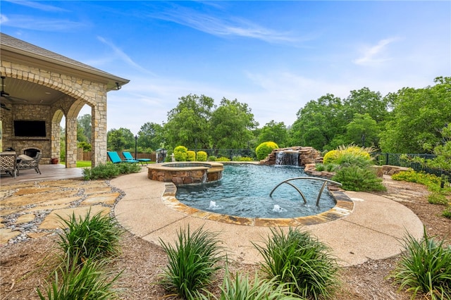 view of pool with pool water feature, ceiling fan, an outdoor stone fireplace, an in ground hot tub, and a patio area