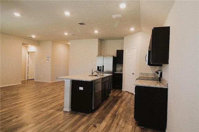 kitchen featuring light stone counters, hardwood / wood-style floors, an island with sink, and stainless steel appliances