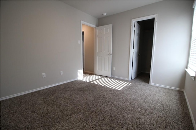 unfurnished bedroom featuring a walk in closet, a closet, and carpet