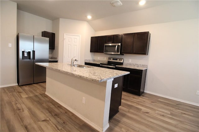 kitchen featuring lofted ceiling, a center island with sink, sink, light hardwood / wood-style flooring, and stainless steel appliances