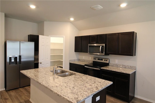 kitchen with light stone counters, stainless steel appliances, a kitchen island with sink, sink, and hardwood / wood-style flooring