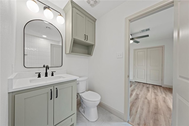 bathroom with hardwood / wood-style floors, vanity, toilet, and ceiling fan