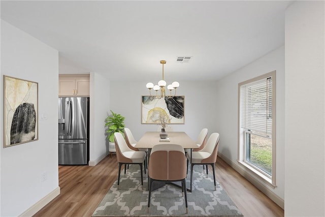 dining area featuring light wood-type flooring and an inviting chandelier