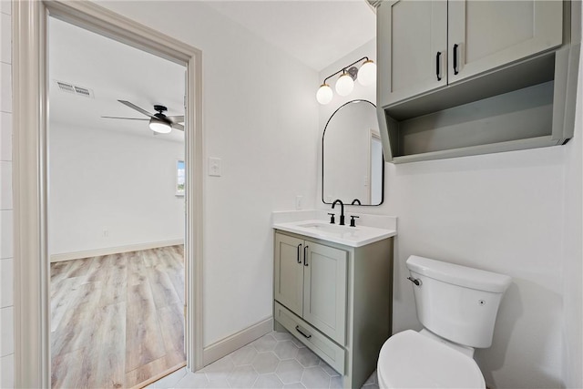 bathroom with ceiling fan, vanity, wood-type flooring, and toilet