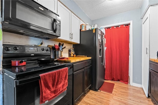 kitchen featuring white cabinetry, light hardwood / wood-style flooring, black appliances, and a textured ceiling