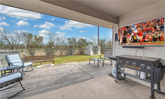 wooden terrace featuring a storage shed, a lawn, an outdoor structure, and a fenced backyard