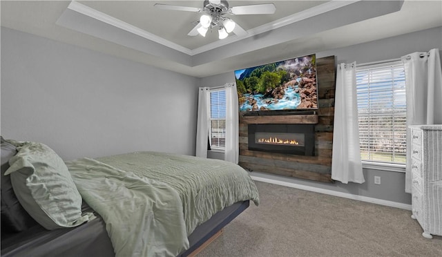 bedroom featuring a large fireplace, baseboards, a tray ceiling, and carpet flooring