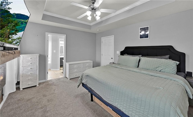 carpeted bedroom with a raised ceiling, ornamental molding, connected bathroom, ceiling fan, and baseboards