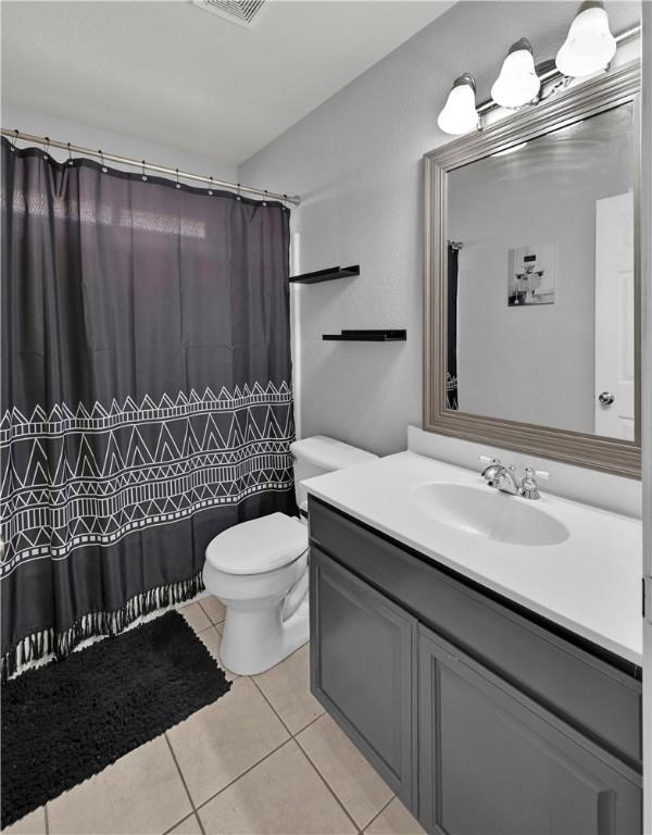 full bathroom with visible vents, toilet, curtained shower, tile patterned flooring, and vanity