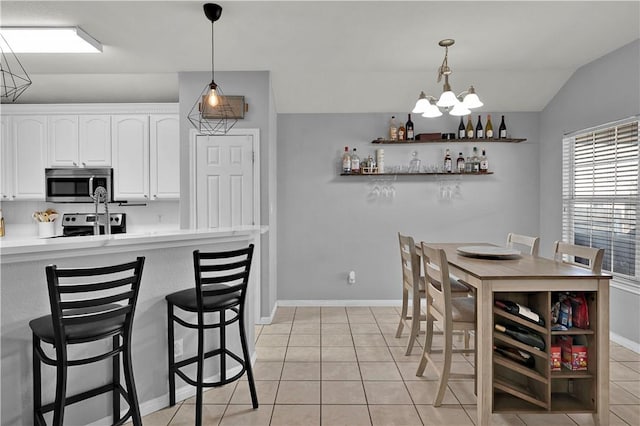 kitchen featuring light tile patterned floors, a breakfast bar, white cabinets, appliances with stainless steel finishes, and open shelves