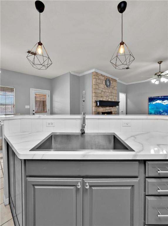 kitchen with decorative light fixtures, gray cabinets, a sink, and open floor plan