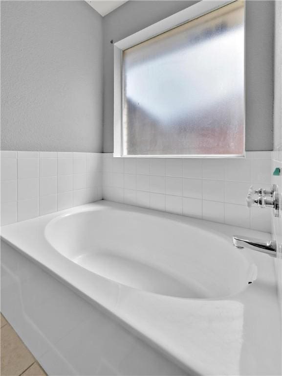 bathroom with tile patterned flooring and a bath