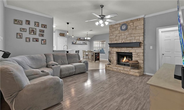 living area featuring a fireplace, crown molding, a ceiling fan, wood finished floors, and baseboards