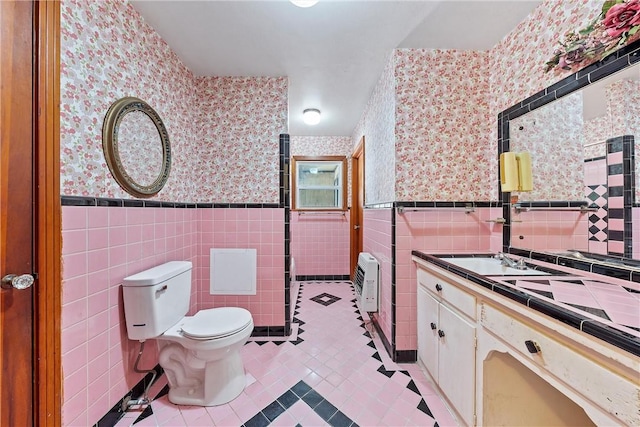 bathroom featuring vanity, heating unit, tile patterned floors, and tile walls