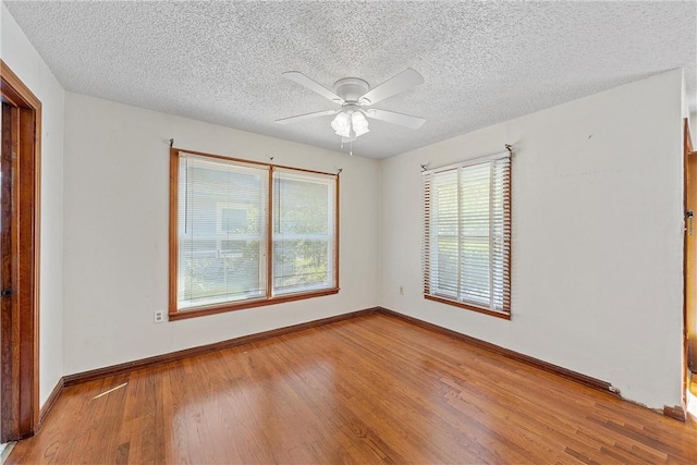 spare room featuring a textured ceiling, light wood-type flooring, and ceiling fan