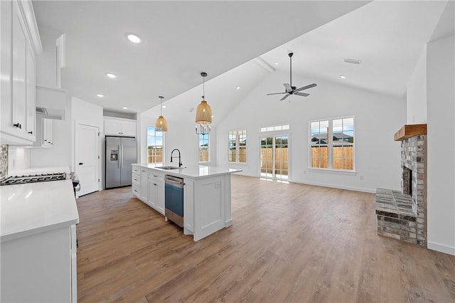 kitchen featuring a healthy amount of sunlight, a center island with sink, white cabinets, and stainless steel appliances