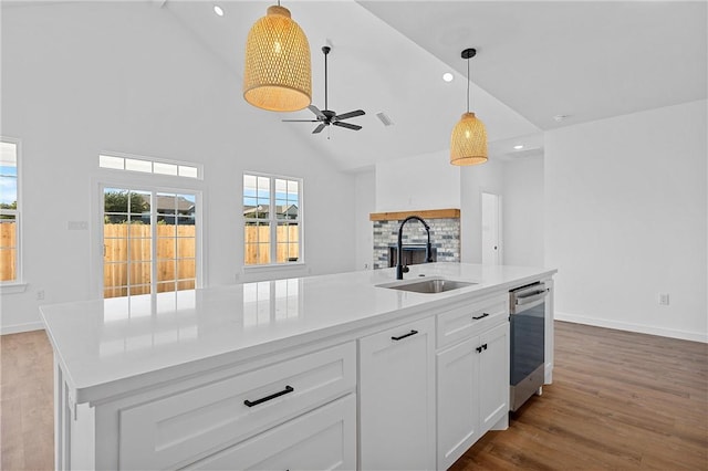 kitchen featuring sink, a center island with sink, high vaulted ceiling, dishwasher, and white cabinets