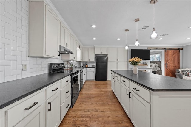 kitchen featuring dark countertops, visible vents, black appliances, under cabinet range hood, and a barn door