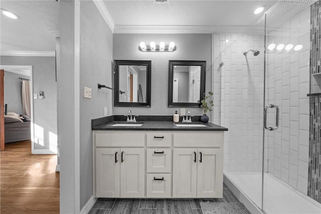 ensuite bathroom featuring wood tiled floor, crown molding, a textured wall, and a sink