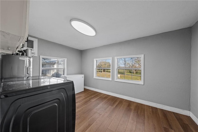 laundry area with laundry area, washer / clothes dryer, wood finished floors, and baseboards