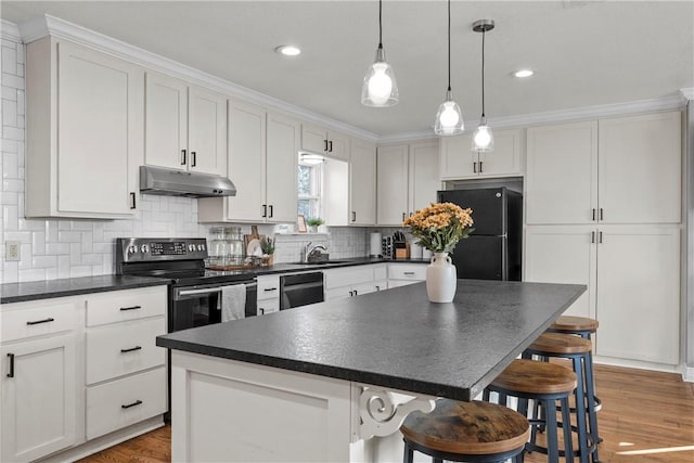 kitchen featuring dark countertops, under cabinet range hood, white cabinets, black appliances, and a sink