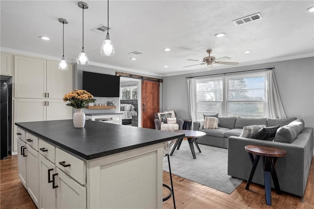 kitchen with a barn door, dark countertops, and visible vents