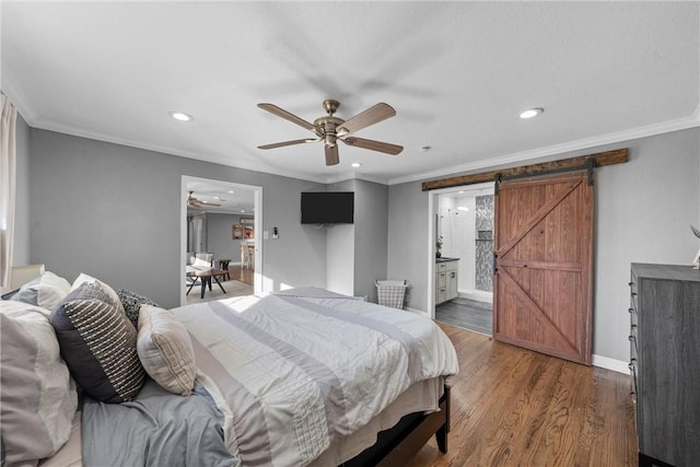 bedroom featuring wood finished floors, baseboards, recessed lighting, crown molding, and a barn door