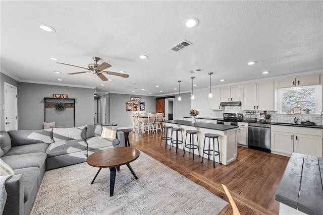 living room featuring visible vents, recessed lighting, crown molding, and dark wood-type flooring