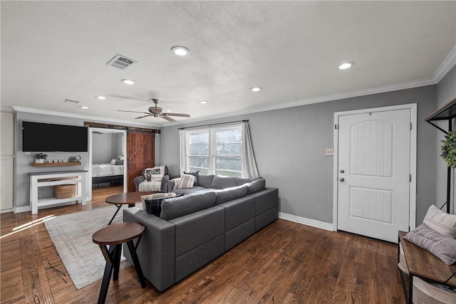 living area with visible vents, a barn door, ornamental molding, wood finished floors, and a textured ceiling