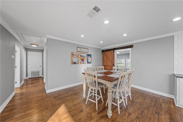 dining room with visible vents, ornamental molding, a barn door, and wood finished floors