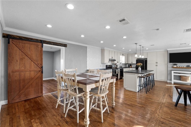 dining room with visible vents, dark wood-type flooring, a barn door, ornamental molding, and recessed lighting