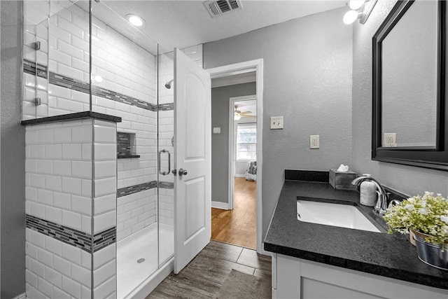 full bath featuring visible vents, wood finished floors, a shower stall, baseboards, and vanity