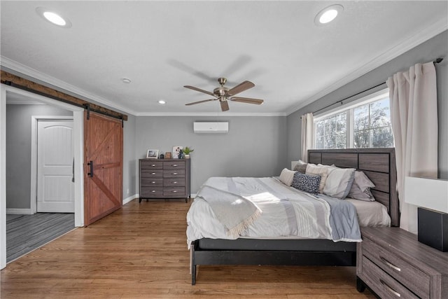 bedroom with a barn door, ornamental molding, wood finished floors, and a wall mounted AC