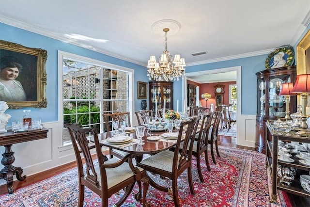 dining space featuring hardwood / wood-style floors, ornamental molding, and a chandelier