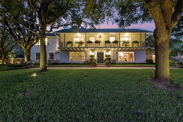 view of front facade featuring a yard, a balcony, and ceiling fan