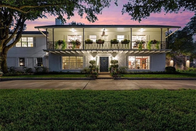 view of front of home with a yard and a balcony