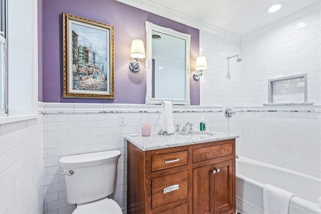 full bathroom with vanity, toilet, tile walls, and tiled shower / bath