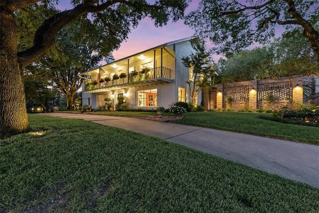 view of front of home featuring a lawn and a balcony