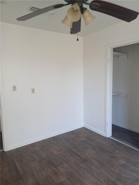 unfurnished bedroom featuring a walk in closet, a closet, ceiling fan, and dark wood-type flooring