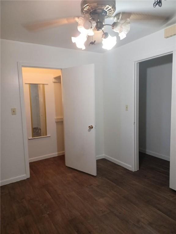 spare room featuring a chandelier and dark wood-type flooring