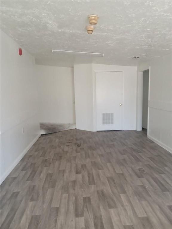 unfurnished room featuring hardwood / wood-style flooring and a textured ceiling