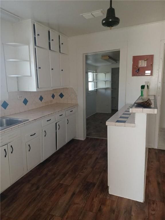 kitchen with tasteful backsplash, white cabinetry, sink, and dark wood-type flooring