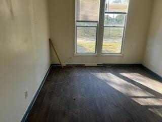 spare room featuring dark hardwood / wood-style flooring and a healthy amount of sunlight