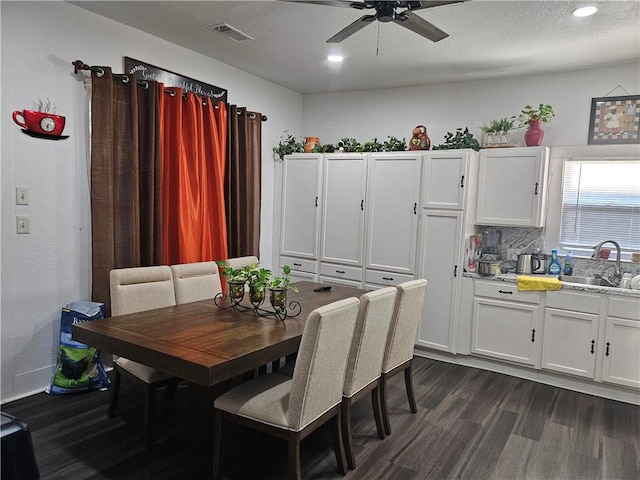 dining area with ceiling fan, sink, dark wood-type flooring, and a textured ceiling