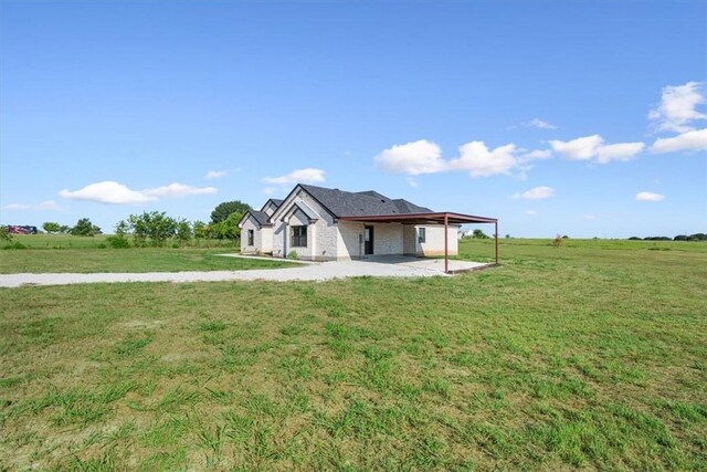 view of front of home with a rural view, a front yard, and a carport