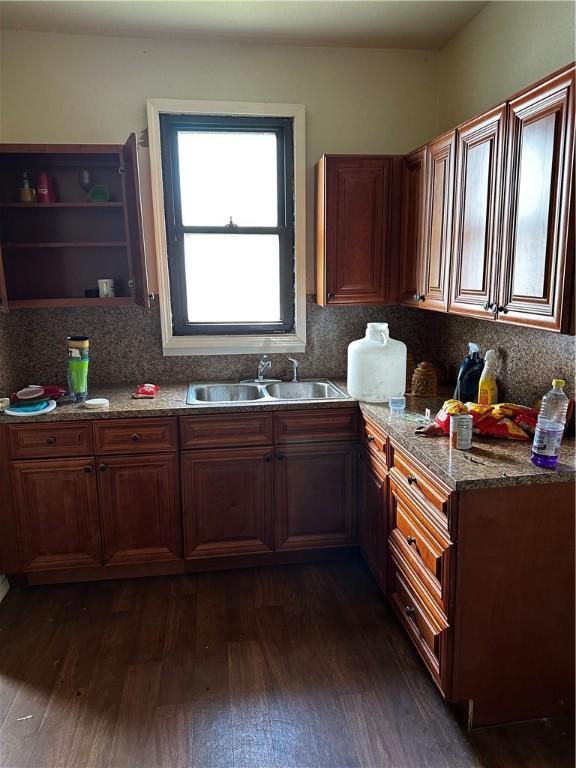 kitchen featuring stone countertops, decorative backsplash, sink, and dark wood-type flooring